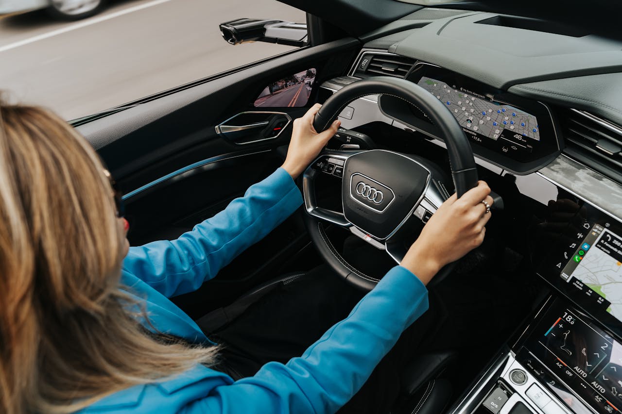 Home High angle view of a woman driving a modern Audi car, showcasing the dashboard and steering wheel.