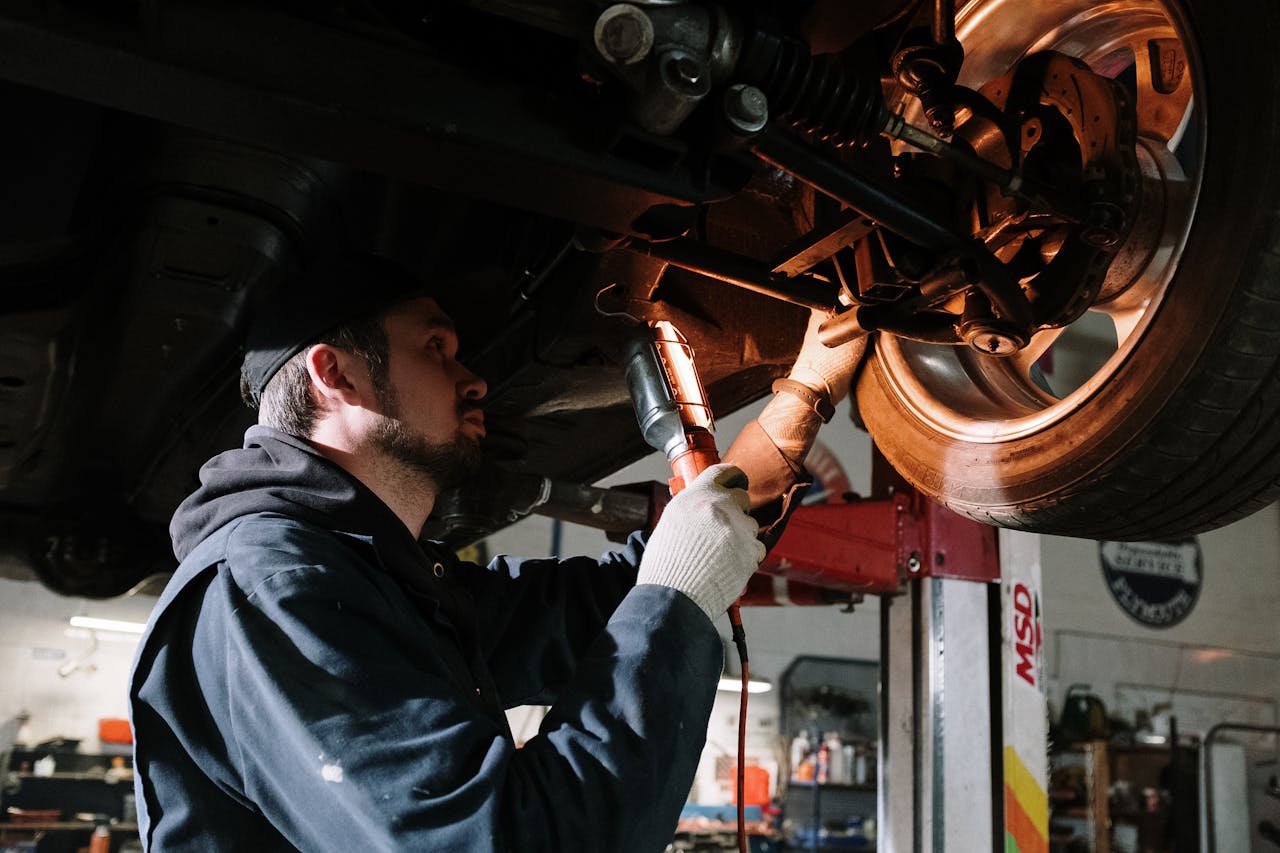 Home Mechanic examining car's undercarriage at a garage, focusing on vehicle maintenance.